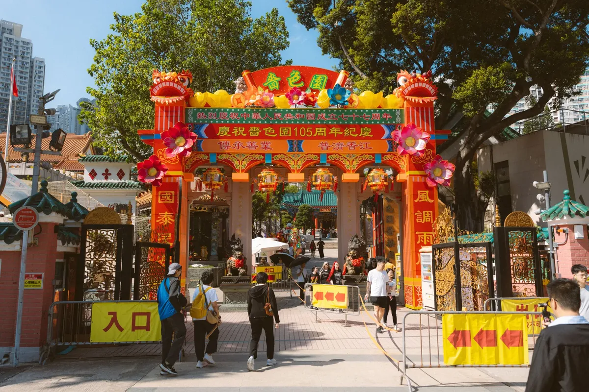 Colorful entrance of Wong Tai Sin Temple in Hong Kong with decorative lanterns and archway.