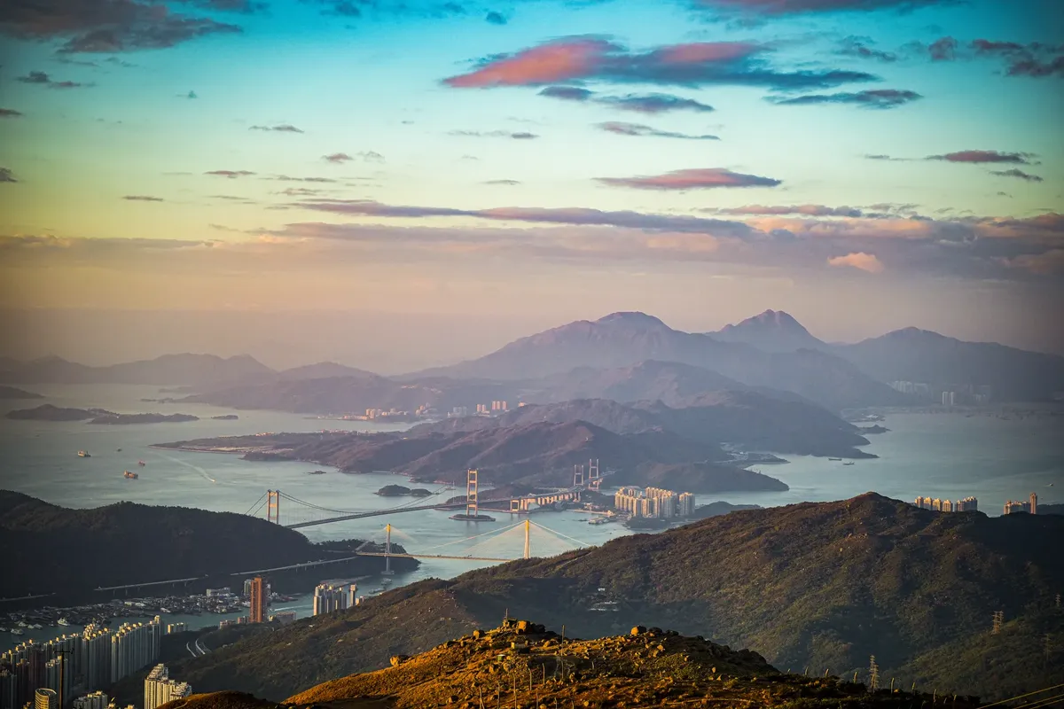 夕方の空の下、ホンコンの島と山々の素晴らしい空撮影、そしてアイコン的な橋が見える