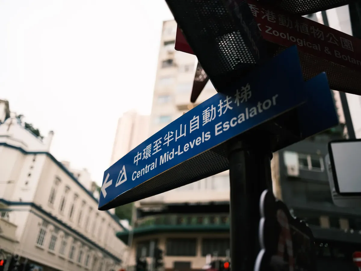 Urban street sign pointing to Central Mid-Levels Escalator in Hong Kong.